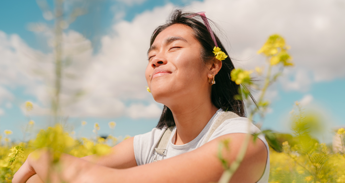 Woman sitting in a field with flowers in Spring.